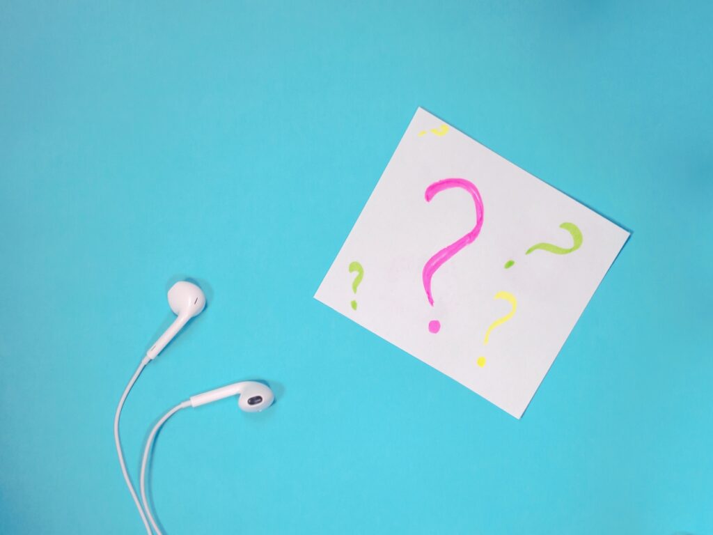 white earphones on a blue background. Paper with question marks