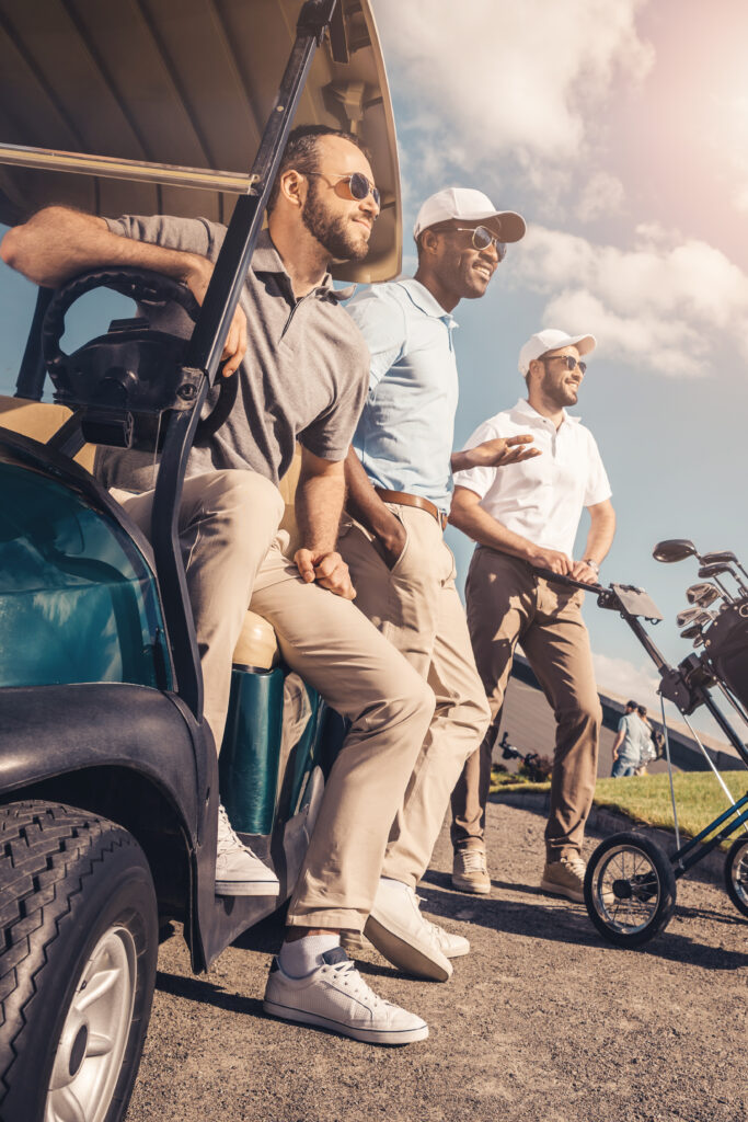 group of multiethnic friends standing near golf cart and looking away