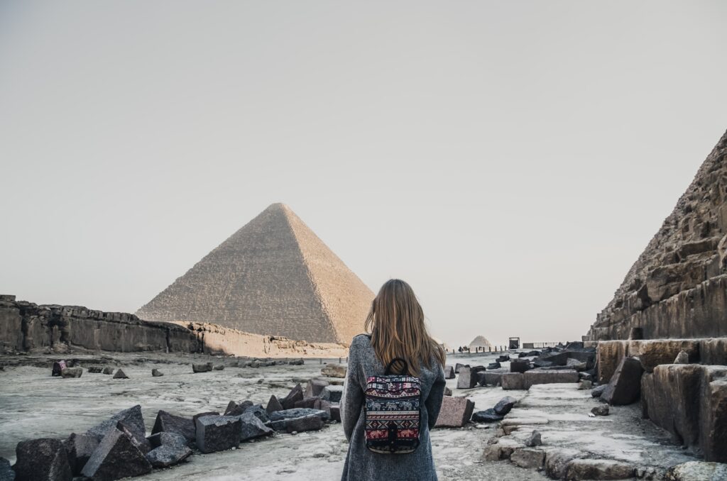 A European blonde walks near the pyramids in the desert in Cairo A European blonde walks near the pyramids in the desert in Cairo. The girl against the background of ancient buildings in Giza.